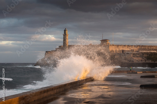 Big waves on Malecon streets during sunrise with storm clouds in background. Havana, Cuba