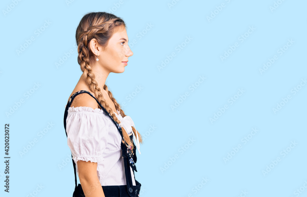Beautiful caucasian woman with blonde hair wearing octoberfest traditional clothes looking to side, relax profile pose with natural face with confident smile.