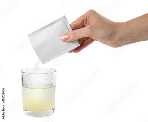 Woman pouring powder from medicine sachet into glass of water on white background, closeup photo