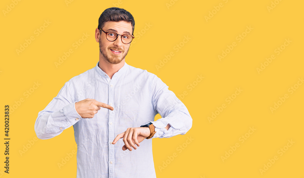 Handsome young man with bear wearing elegant business shirt and glasses in hurry pointing to watch time, impatience, upset and angry for deadline delay Handsome young man with bear wearing elegant business shirt and glasses in hurry pointing to watch time, impatience, upset and angry for deadline delay