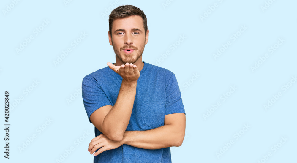 Handsome caucasian man wearing casual clothes looking at the camera blowing a kiss with hand on air being lovely and sexy. love expression. Handsome caucasian man wearing casual clothes looking at the camera blowing a kiss with hand on air being lovely and sexy. love expression.