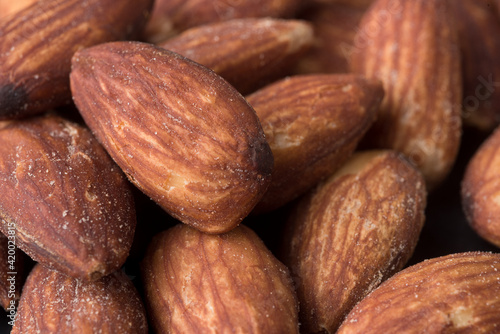 Pile of salted and roasted almond on dark background