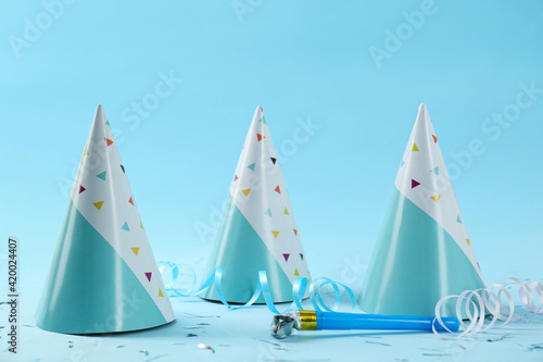 Bright party hats, horn, serpentine streamers and confetti on light blue background