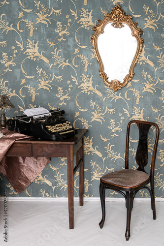 Vintage old style typewriter on the retro table. Retro interior with the old furniture and vintege mirror on the wall. photo