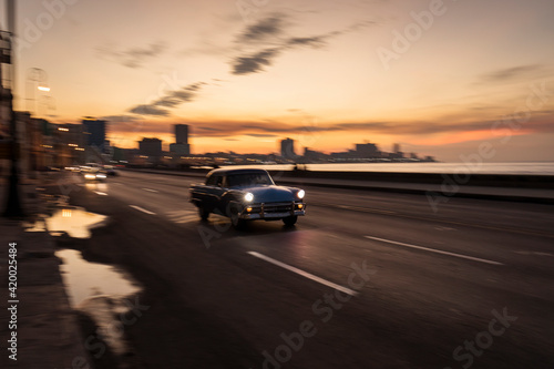 Old car on Malecon street of Havana with colourful sunset in background. Cuba