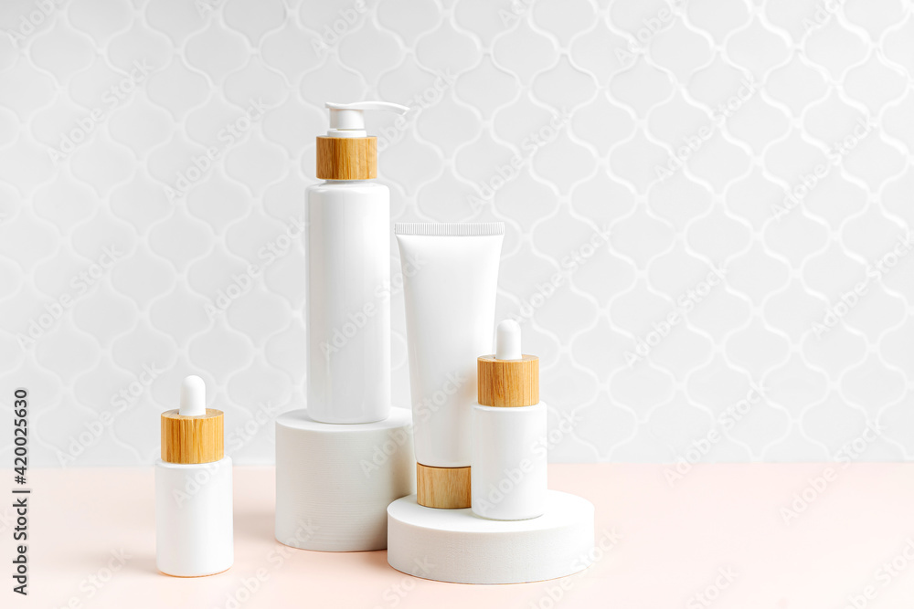 Pump bottle, cream tube, and dropper on table in bathroom. Cosmetic container mock-ups. Background for branding and packaging presentation. Natural skincare beauty product concept. Pump bottle, cream tube, and dropper on table in bathroom. Cosmetic container mock-ups. Background for branding and packaging presentation. Natural skincare beauty product concept.