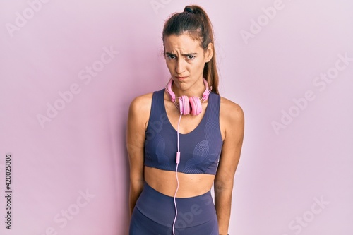 Young beautiful woman wearing gym clothes and using headphones skeptic and nervous, frowning upset because of problem. negative person. © Krakenimages.com