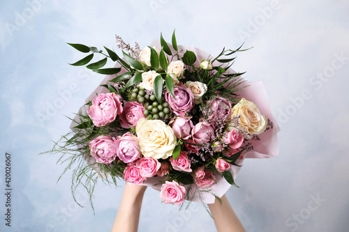 Fotografia Woman with bouquet of beautiful roses on light blue background, closeup