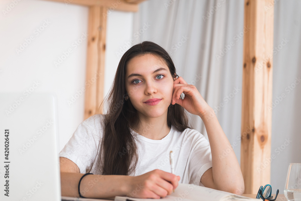Young girl student video chatting or online calling, sit at the table with laptop Young girl student video chatting or online calling, sit at the table with laptop