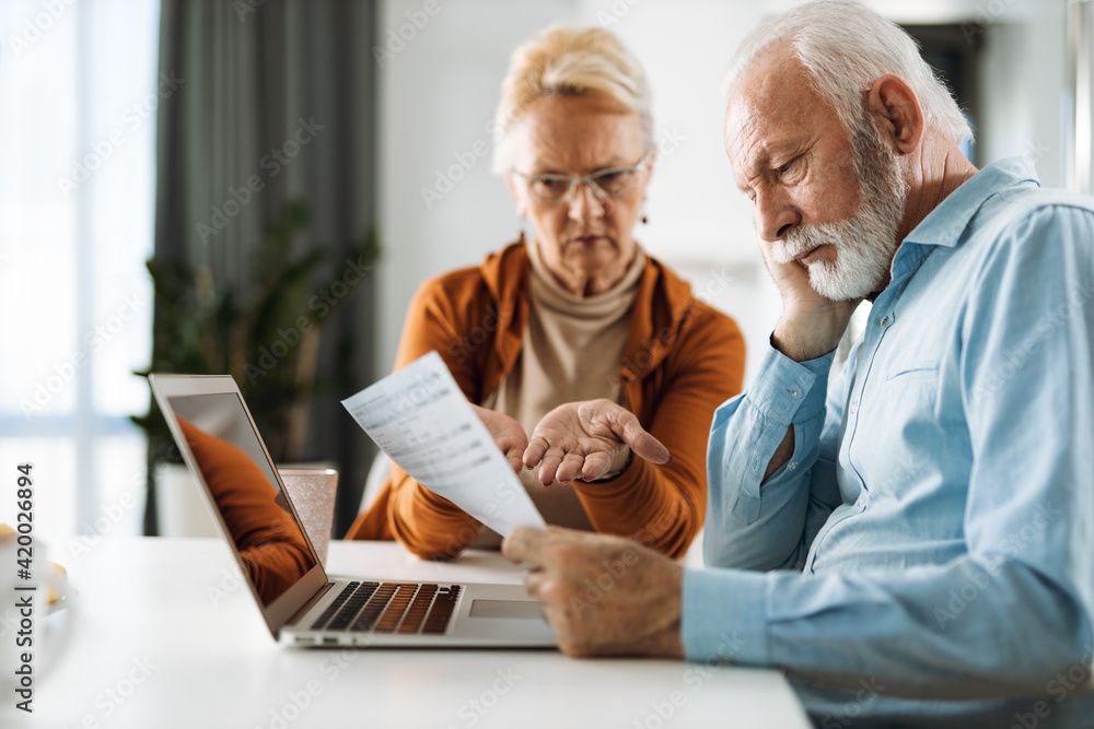 Frustrated senior couple sitting at home and checking their home finance