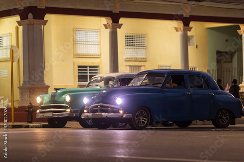 Amazing old american car on streets of Havana with colourful buildings in background during the night. Havana, Cuba.