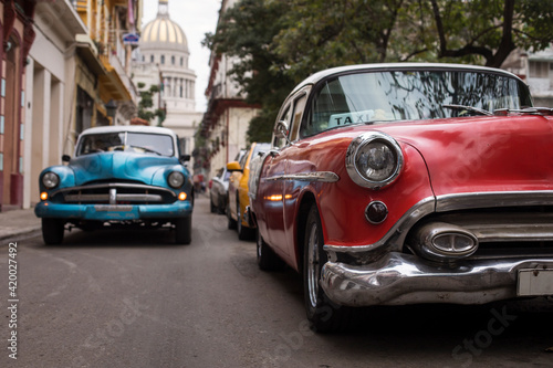 Old car on streets of Havana with colourful buildings in background. Cuba