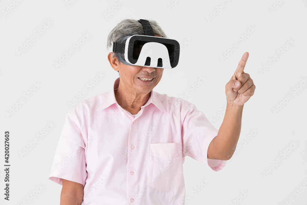 Portrait of full energy and active senior older Asian man wearing virtual reality device on head and enjoy with game and entertainment. VR new technology learning concept for old people Portrait of full energy and active senior older Asian man wearing virtual reality device on head and enjoy with game and entertainment. VR new technology learning concept for old people