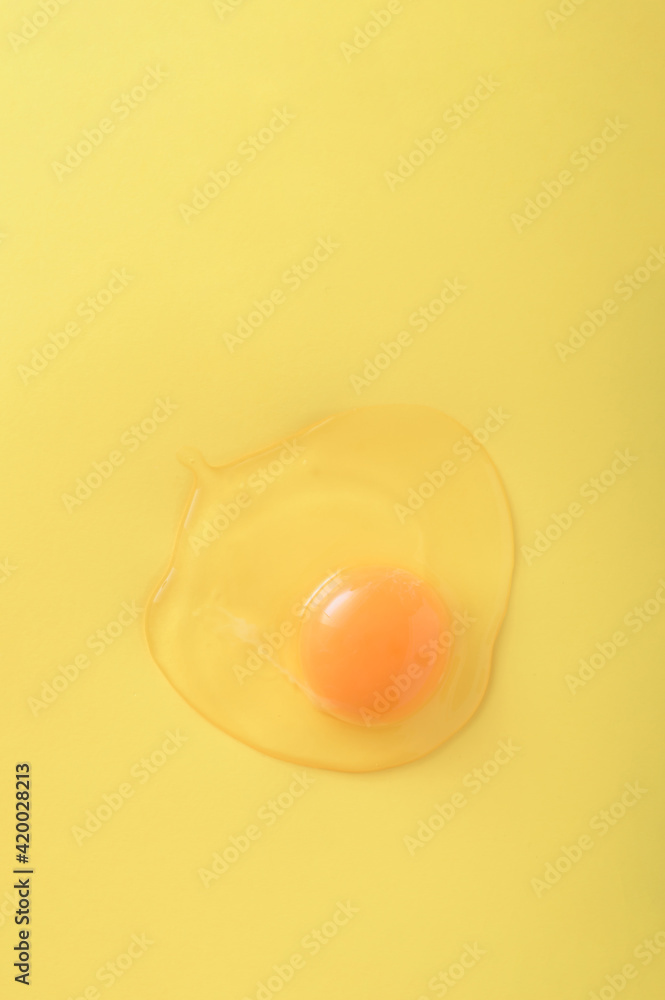 Raw egg on a yellow background with copy space. Easter concept 2021. Healthy food. Trendy color.