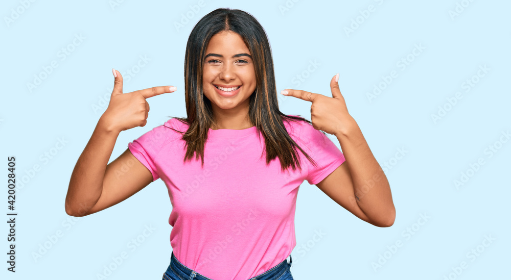 Young latin girl wearing casual clothes smiling cheerful showing and pointing with fingers teeth and mouth. dental health concept. Young latin girl wearing casual clothes smiling cheerful showing and pointing with fingers teeth and mouth. dental health concept.