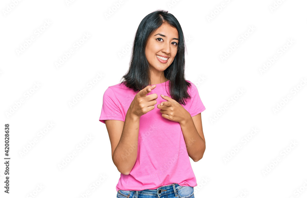 Beautiful asian young woman wearing casual pink t shirt pointing fingers to camera with happy and funny face. good energy and vibes. Beautiful asian young woman wearing casual pink t shirt pointing fingers to camera with happy and funny face. good energy and vibes.