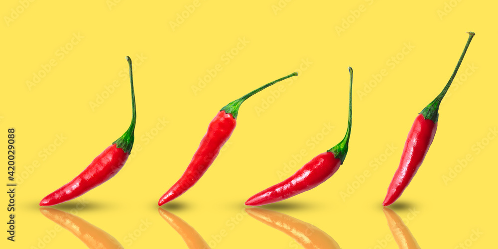Small hot red chilli peppers arranged in a row on a yellow background Small hot red chilli peppers arranged in a row on a yellow background