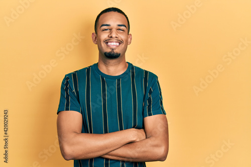 Young african american man wearing casual clothes happy face smiling with crossed arms looking at the camera. positive person. © Krakenimages.com