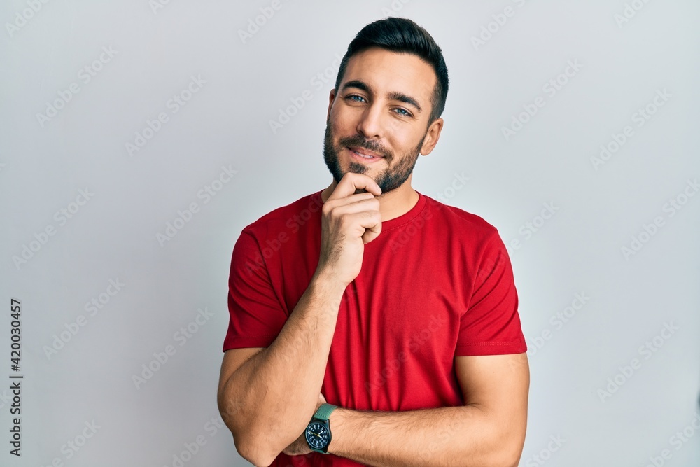Young hispanic man wearing casual clothes looking confident at the camera with smile with crossed arms and hand raised on chin. thinking positive. Young hispanic man wearing casual clothes looking confident at the camera with smile with crossed arms and hand raised on chin. thinking positive.
