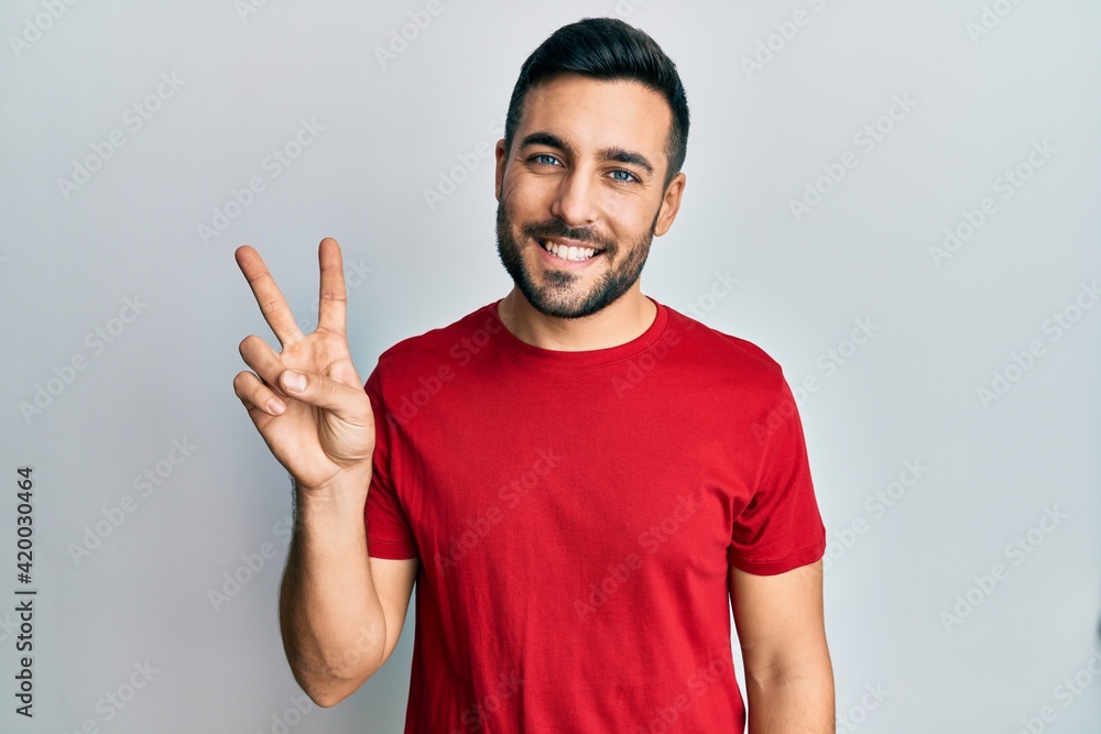 Young hispanic man wearing casual clothes showing and pointing up with fingers number two while smiling confident and happy. Young hispanic man wearing casual clothes showing and pointing up with fingers number two while smiling confident and happy.