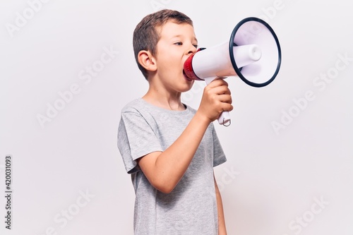 Adorable caucasian kid boy with angry expression. Screaming loud using megaphone standing over isolated white background