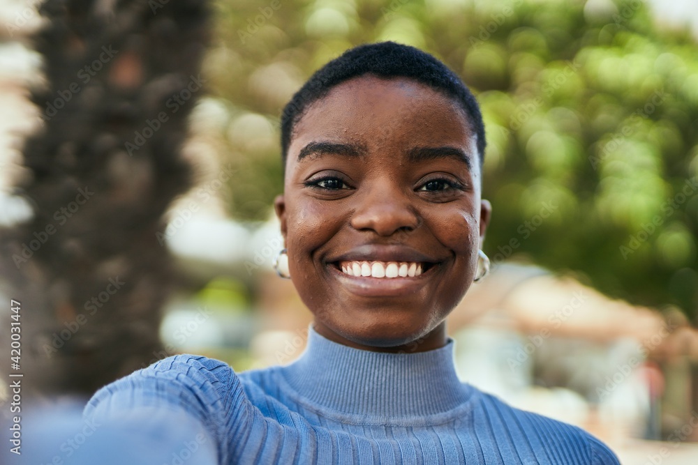 Young african american woman smiling happy making selfie by the camera at the city. Young african american woman smiling happy making selfie by the camera at the city.