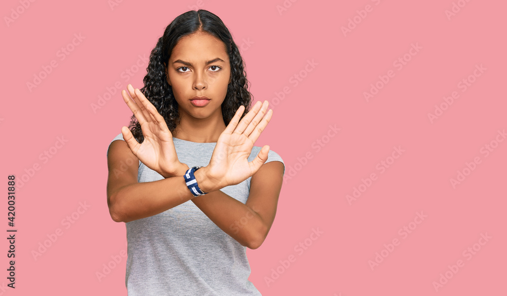 Young african american girl wearing casual clothes rejection expression crossing arms and palms doing negative sign, angry face Young african american girl wearing casual clothes rejection expression crossing arms and palms doing negative sign, angry face