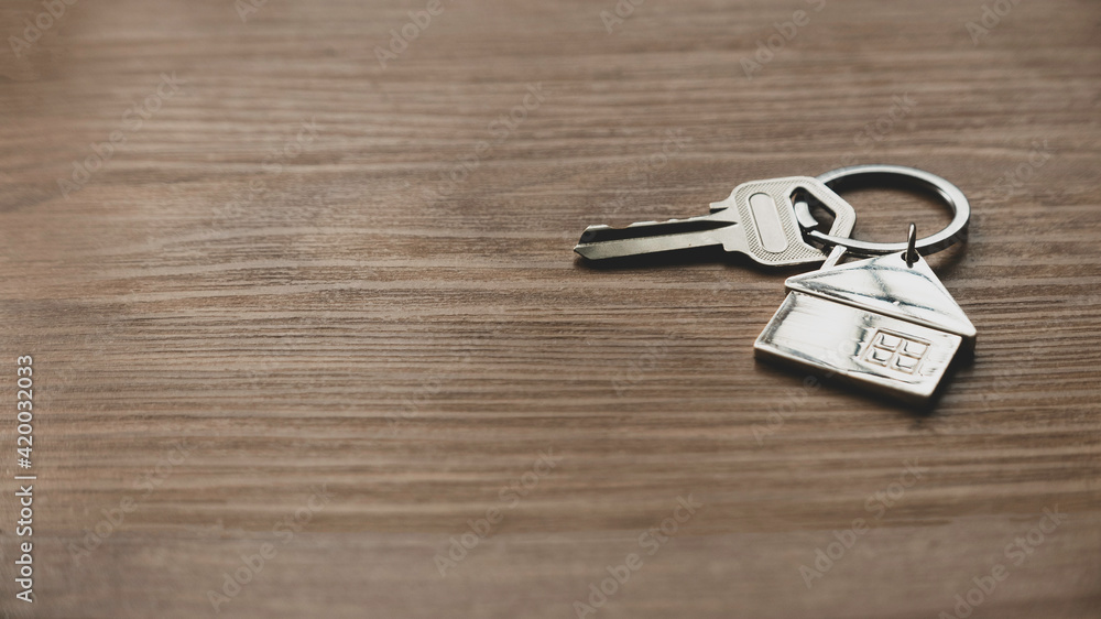 Real estate or property concept. Selective focus of key and house keychain on wooden background with copy space. Real estate or property concept. Selective focus of key and house keychain on wooden background with copy space.