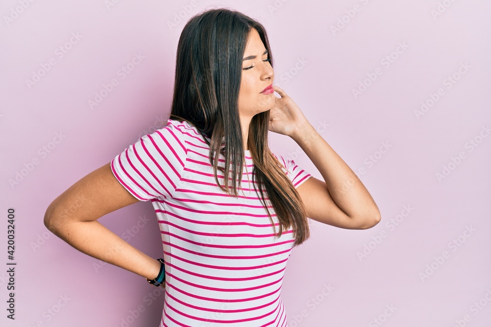 Young brunette woman wearing casual clothes over pink background suffering of neck ache injury, touching neck with hand, muscular pain Young brunette woman wearing casual clothes over pink background suffering of neck ache injury, touching neck with hand, muscular pain