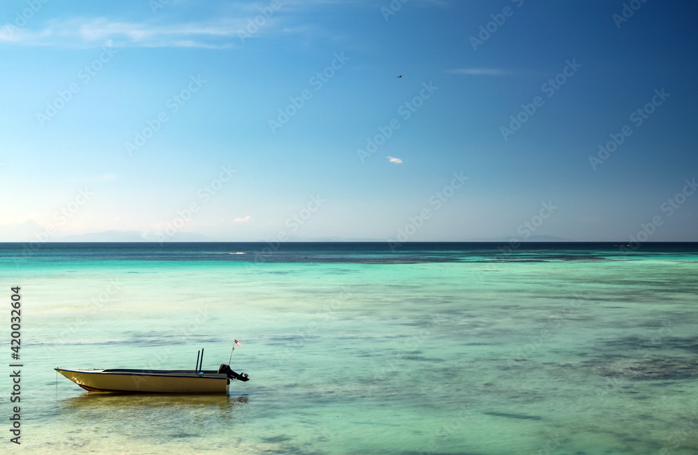 Motor boat standing on shallow water, bright blue sky and turquoise sea water