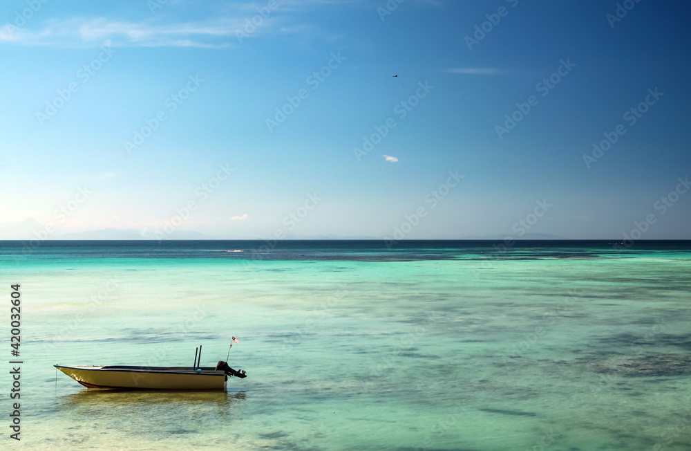 Motor boat standing on shallow water, bright blue sky and turquoise sea water Motor boat standing on shallow water, bright blue sky and turquoise sea water