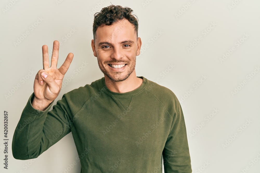 Young hispanic man wearing casual clothes showing and pointing up with fingers number three while smiling confident and happy. Young hispanic man wearing casual clothes showing and pointing up with fingers number three while smiling confident and happy.