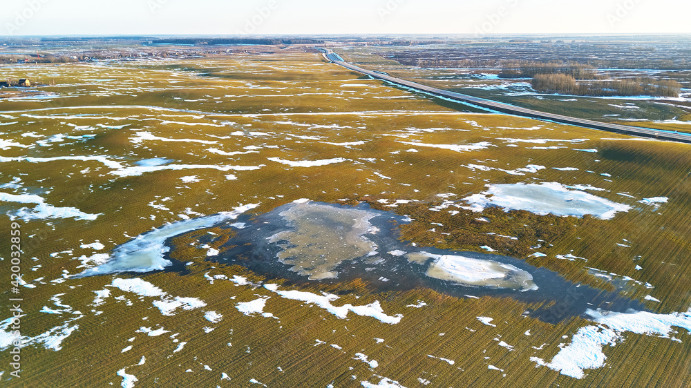 Spring fields aerial view. Snow melting, water pools on meadows. Season change.