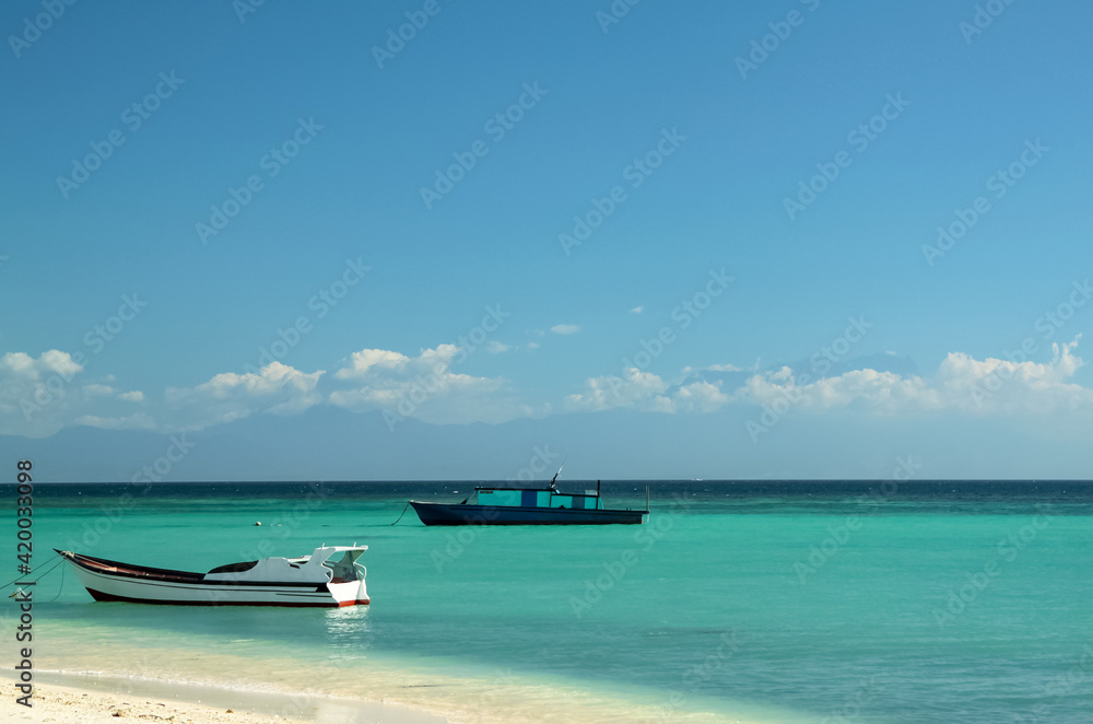 Two boats standing on turquoise water on blue sky background