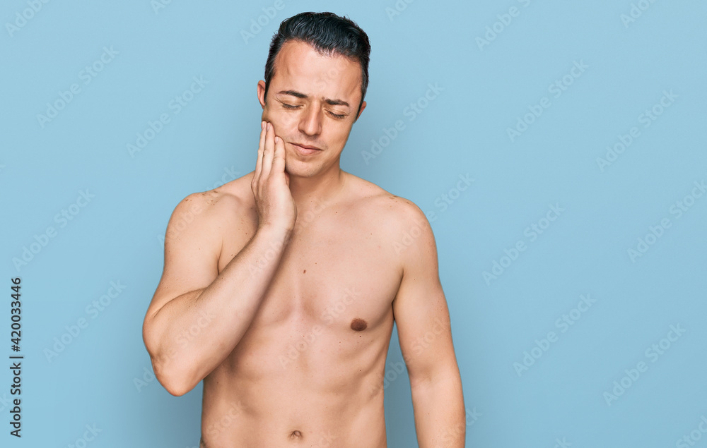 Handsome young man wearing swimwear shirtless touching mouth with hand with painful expression because of toothache or dental illness on teeth. dentist Handsome young man wearing swimwear shirtless touching mouth with hand with painful expression because of toothache or dental illness on teeth. dentist
