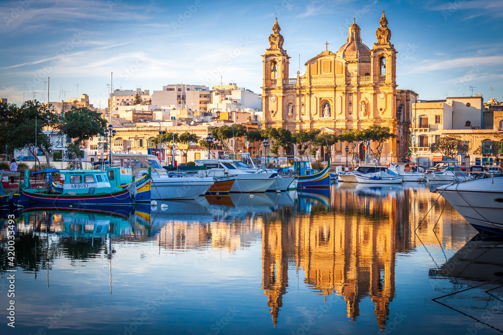 malta, big church at sunset in front of a port with reflection