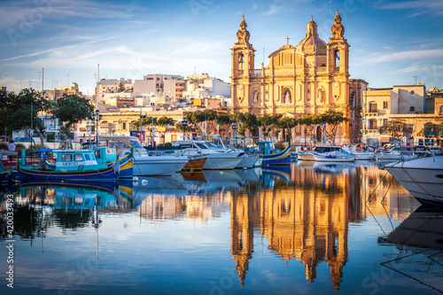 malta, big church at sunset in front of a port with reflection