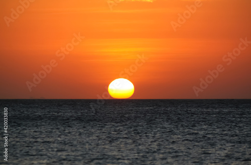 warm sunset over seawater  sun touching seawater on the horizon