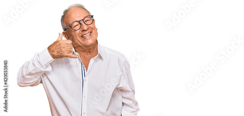 Senior caucasian man wearing business shirt and glasses smiling doing phone gesture with hand and fingers like talking on the telephone. communicating concepts. © Krakenimages.com
