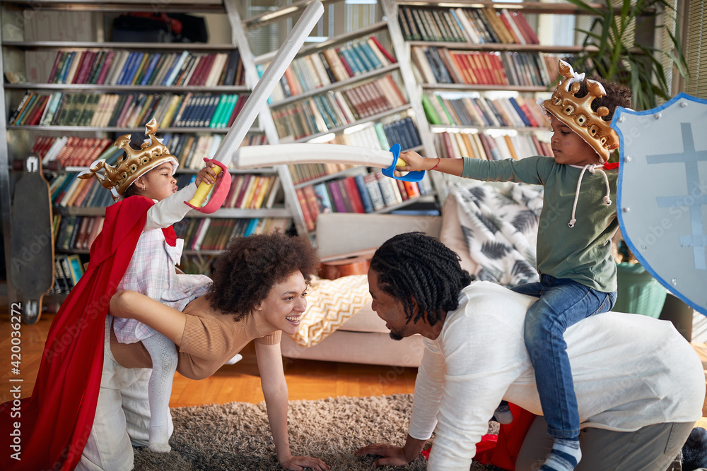 Obraz premium Kids are enjoying riding their parents while imitating knights at home. Family, home, love, together