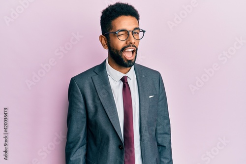 Handsome hispanic business man with beard wearing business suit and tie winking looking at the camera with sexy expression, cheerful and happy face.