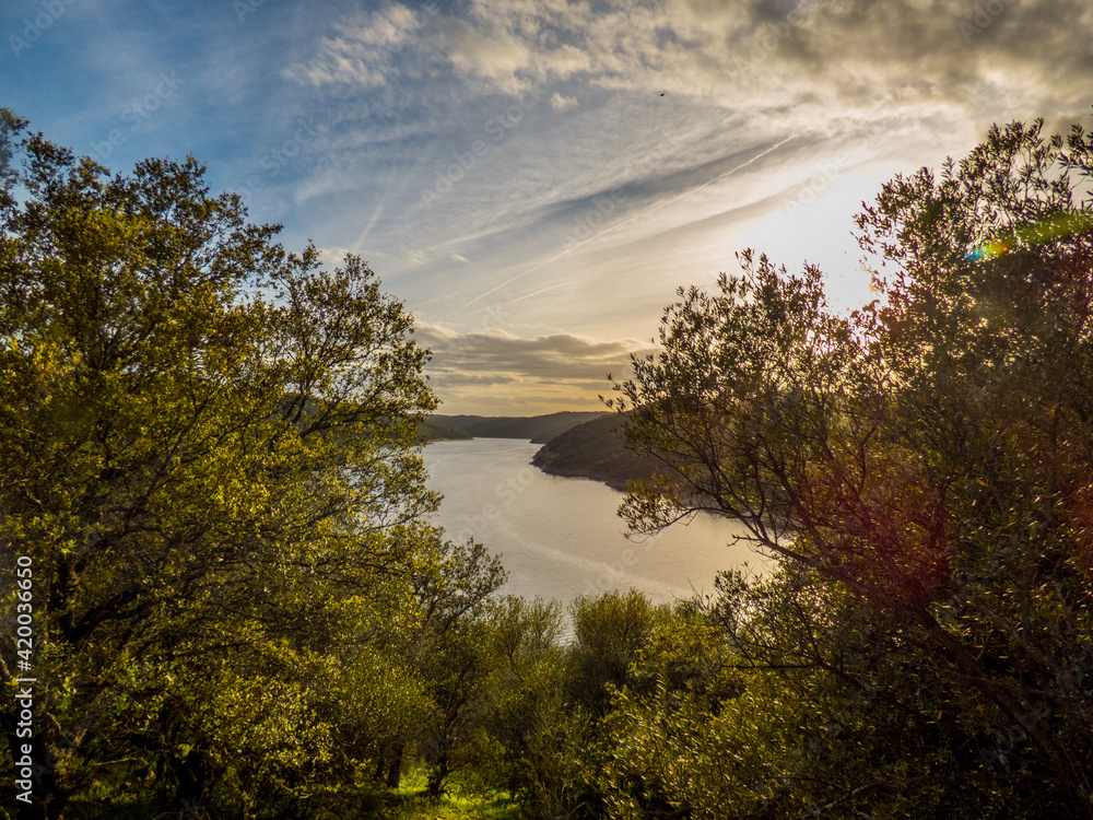 Puesta del sol entre dos alcornoques y con un embalse al fondo en el Parque Nacional de Monfragüe, España Puesta del sol entre dos alcornoques y con un embalse al fondo en el Parque Nacional de Monfragüe, España