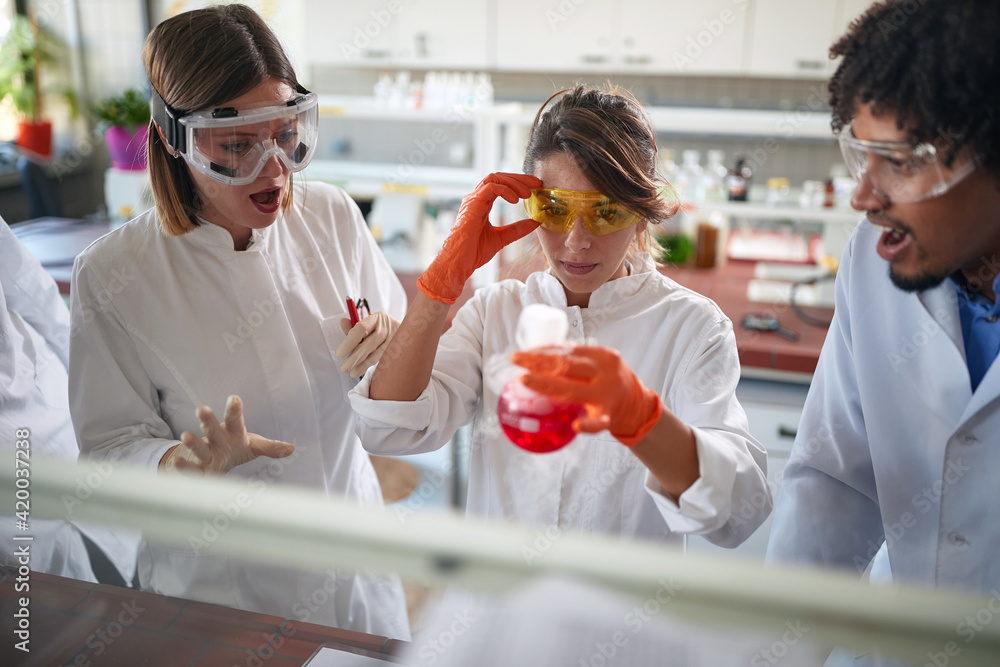 Young excited chemistry students are observing a chemical reaction in an experiment they doing in a laboratory. Science, chemistry, lab, people Young excited chemistry students are observing a chemical reaction in an experiment they doing in a laboratory. Science, chemistry, lab, people