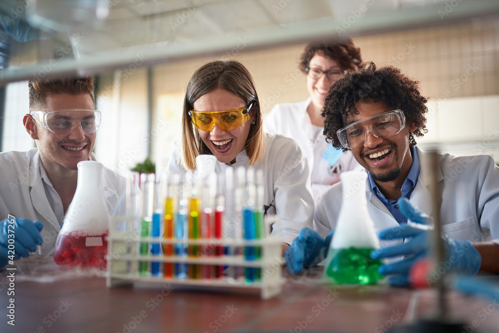 Young chemistry students having a good time in a laboratory while enjoying observing colorful chemical reactions. Science, chemistry, lab, people Young chemistry students having a good time in a laboratory while enjoying observing colorful chemical reactions. Science, chemistry, lab, people