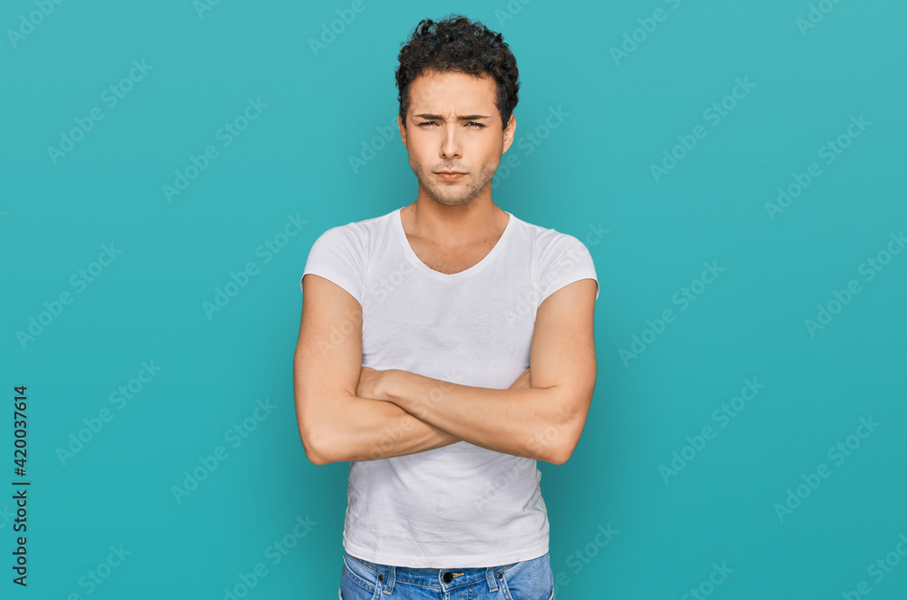Young handsome man wearing casual white t shirt skeptic and nervous, disapproving expression on face with crossed arms. negative person. Young handsome man wearing casual white t shirt skeptic and nervous, disapproving expression on face with crossed arms. negative person.