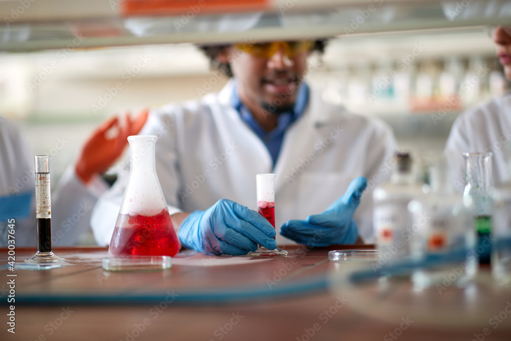 Young colleagues in a protective gear discuss about an experiment they doing in the university laboratory. Science, chemistry, lab, people Young colleagues in a protective gear discuss about an experiment they doing in the university laboratory. Science, chemistry, lab, people