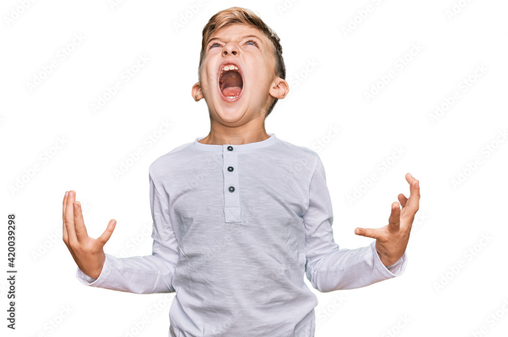 Little caucasian boy kid wearing casual clothes crazy and mad shouting and yelling with aggressive expression and arms raised. frustration concept. Little caucasian boy kid wearing casual clothes crazy and mad shouting and yelling with aggressive expression and arms raised. frustration concept.