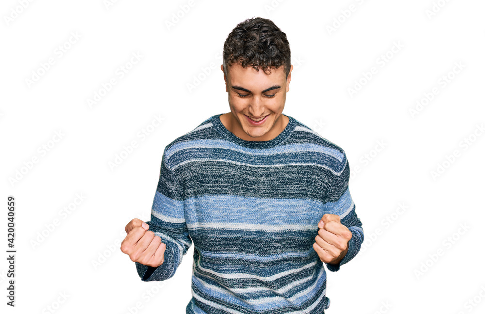 Hispanic young man wearing casual clothes very happy and excited doing winner gesture with arms raised, smiling and screaming for success. celebration concept. Hispanic young man wearing casual clothes very happy and excited doing winner gesture with arms raised, smiling and screaming for success. celebration concept.