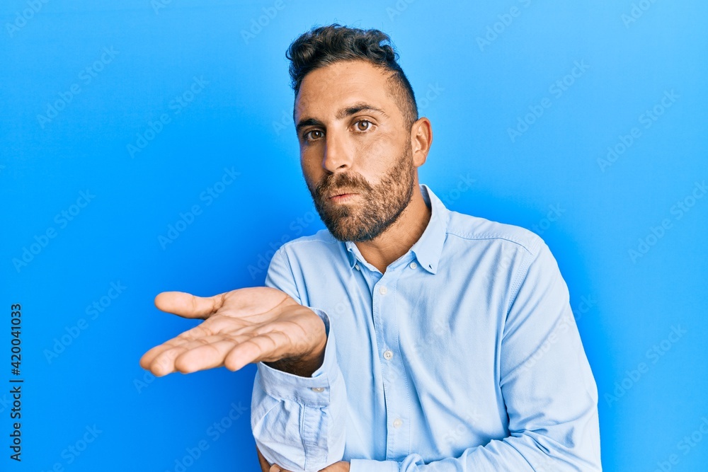Handsome man with beard wearing casual clothes looking at the camera blowing a kiss with hand on air being lovely and sexy. love expression. Handsome man with beard wearing casual clothes looking at the camera blowing a kiss with hand on air being lovely and sexy. love expression.