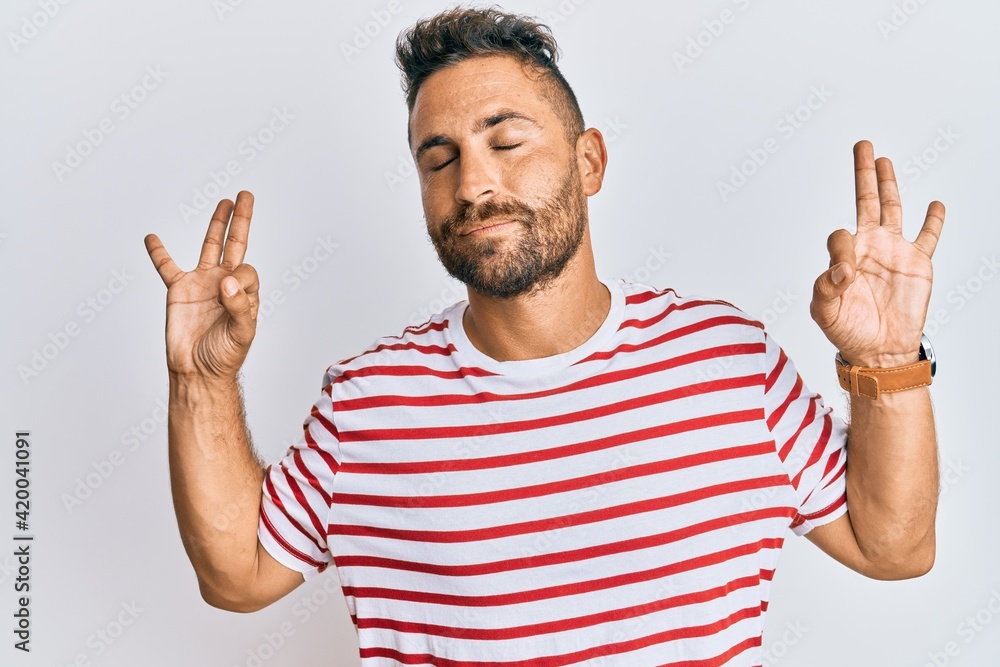 Handsome man with beard wearing casual clothes relax and smiling with eyes closed doing meditation gesture with fingers. yoga concept. Handsome man with beard wearing casual clothes relax and smiling with eyes closed doing meditation gesture with fingers. yoga concept.